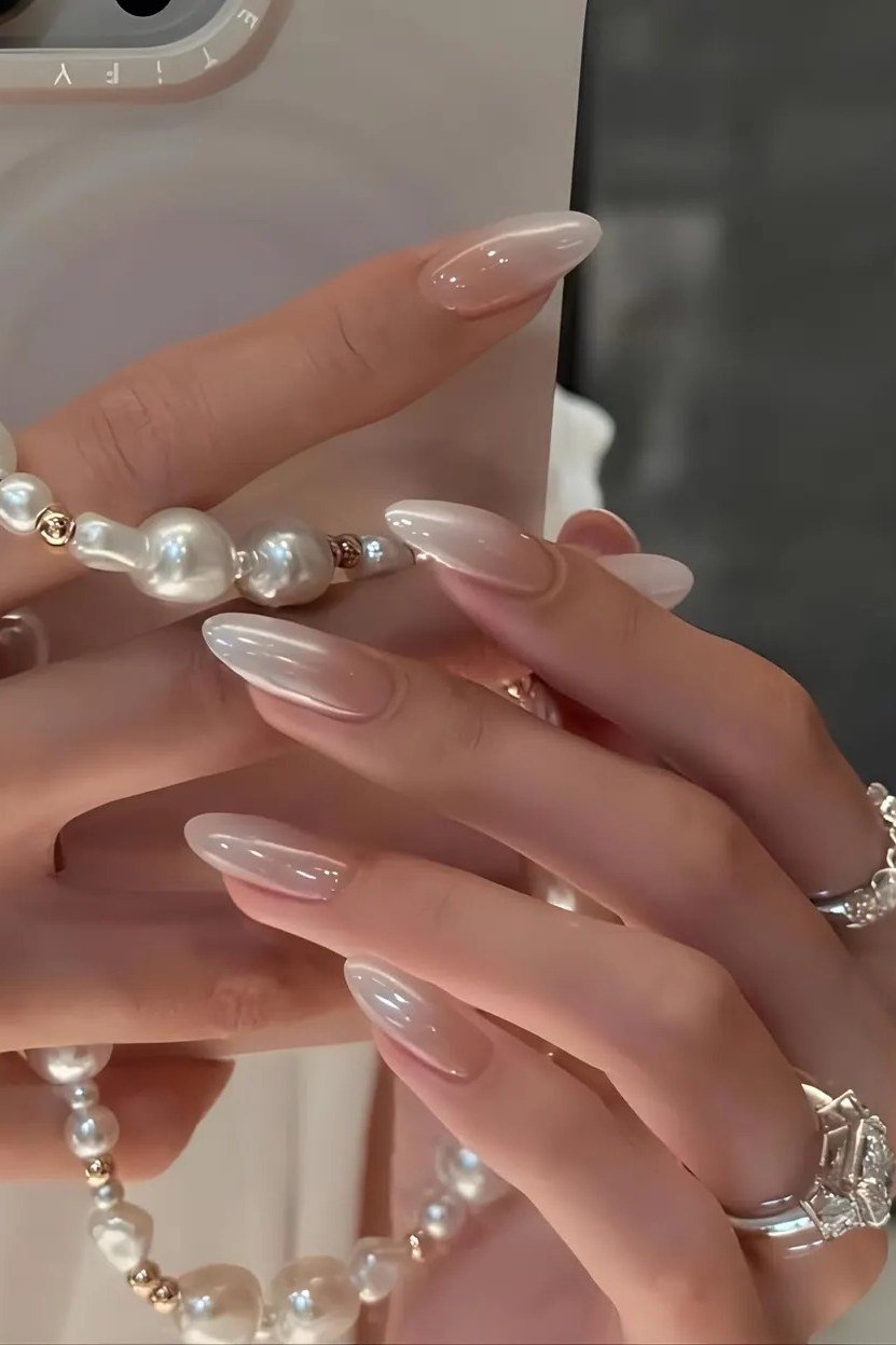 Milky white nails paired with stacked pearl bracelets