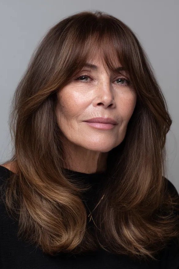 Long chestnut-brown layered hair with curtain bangs for women over 50