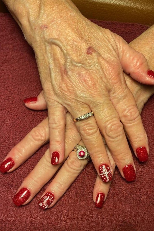 Red nails with white snowflake accent nail art