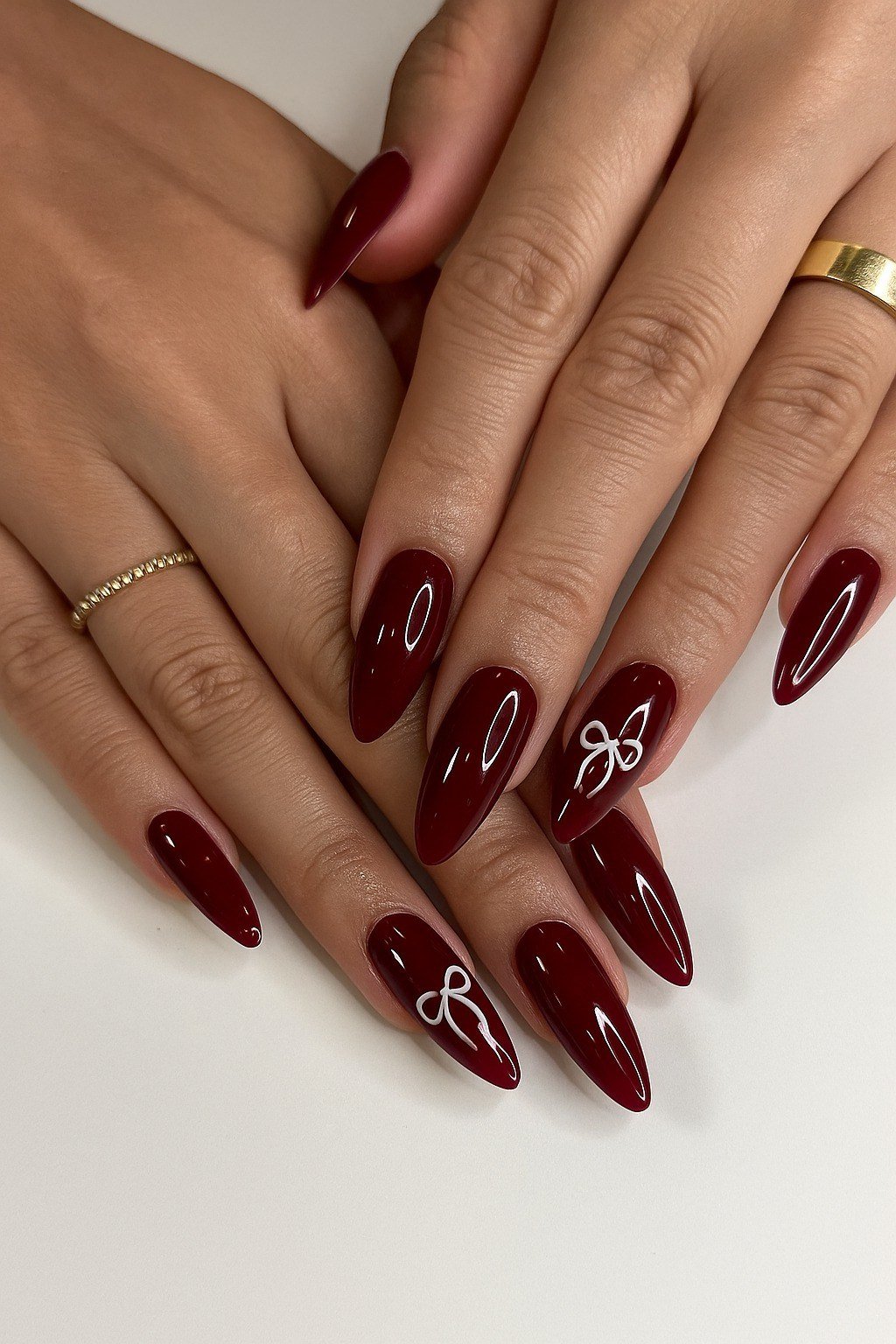 Burgundy almond gel nails with delicate white bow line art, fall nail art