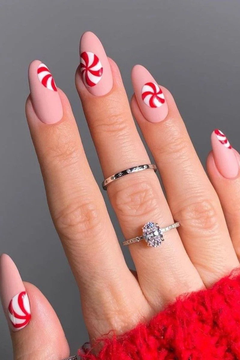pink christmas nails with peppermint swirl accents