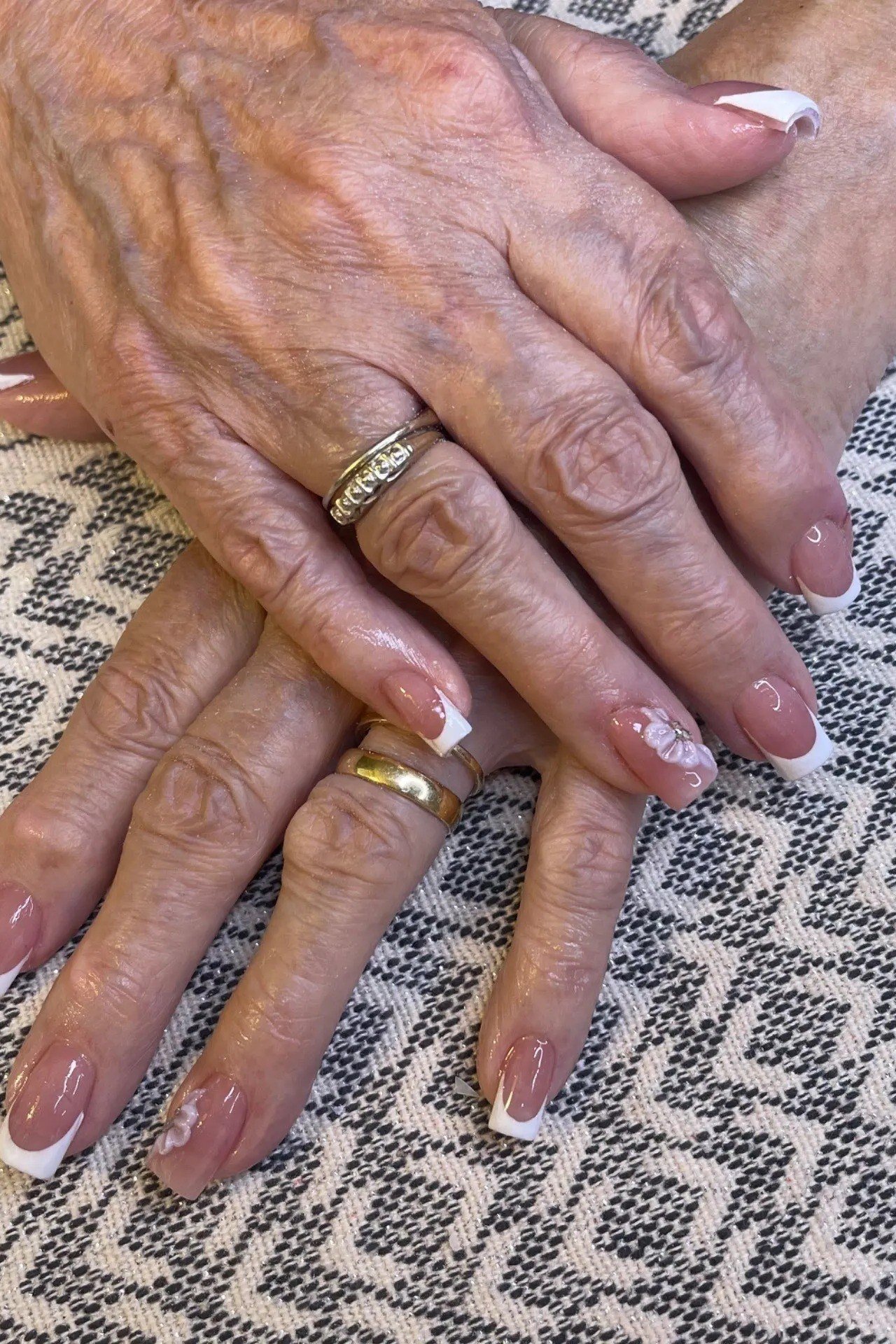 White and gold french manicure on aged hands