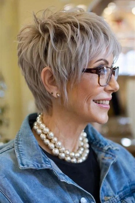 blonde textured pixie with wispy bangs and glasses, smiling 3/4 view hairstyle for women over 70