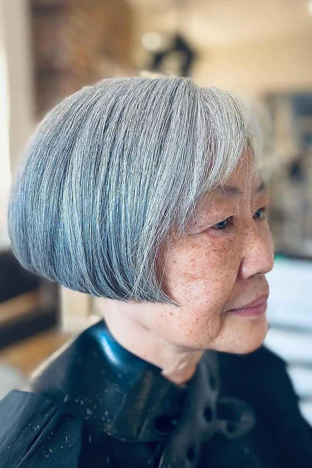 Silver-grey french bob with straight fringe in side view