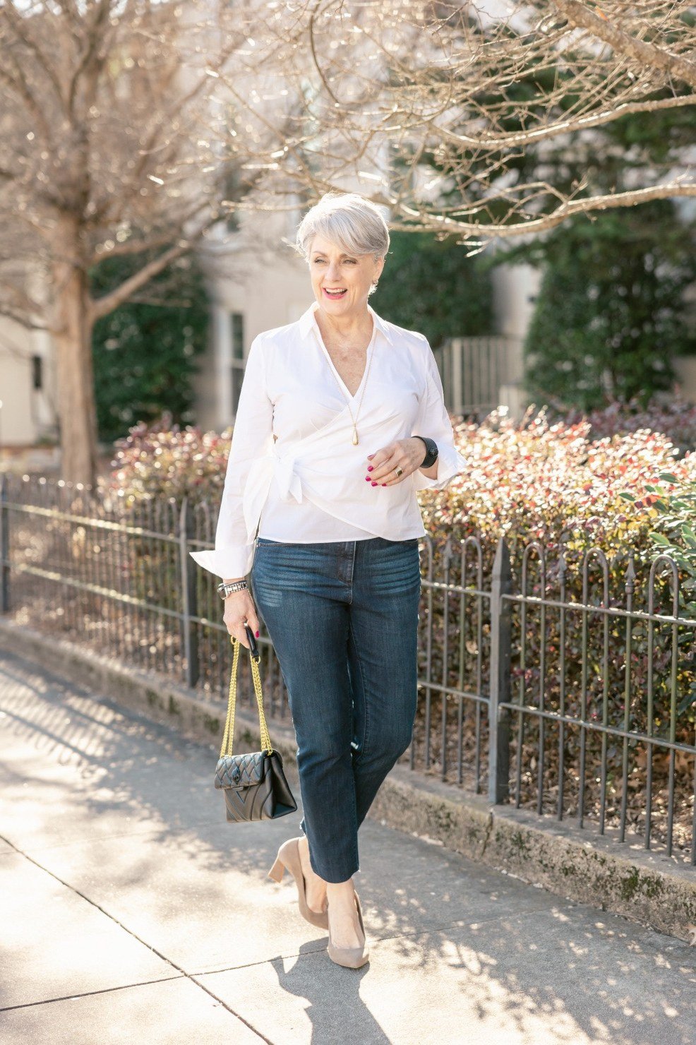 Woman over 60 wearing white blouse, medium jeans, street