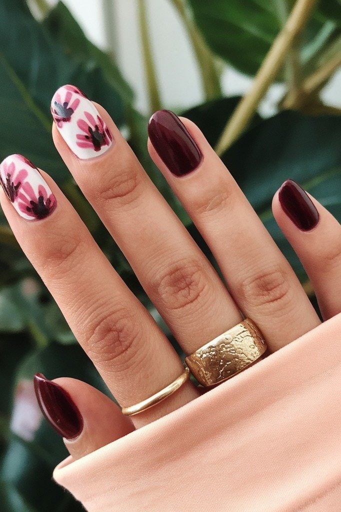 Burgundy nails with floral accent and gold rings for women over 50