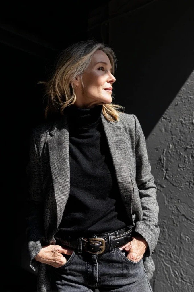 Gray blazer over a black turtleneck and dark trousers for women over 50 at work