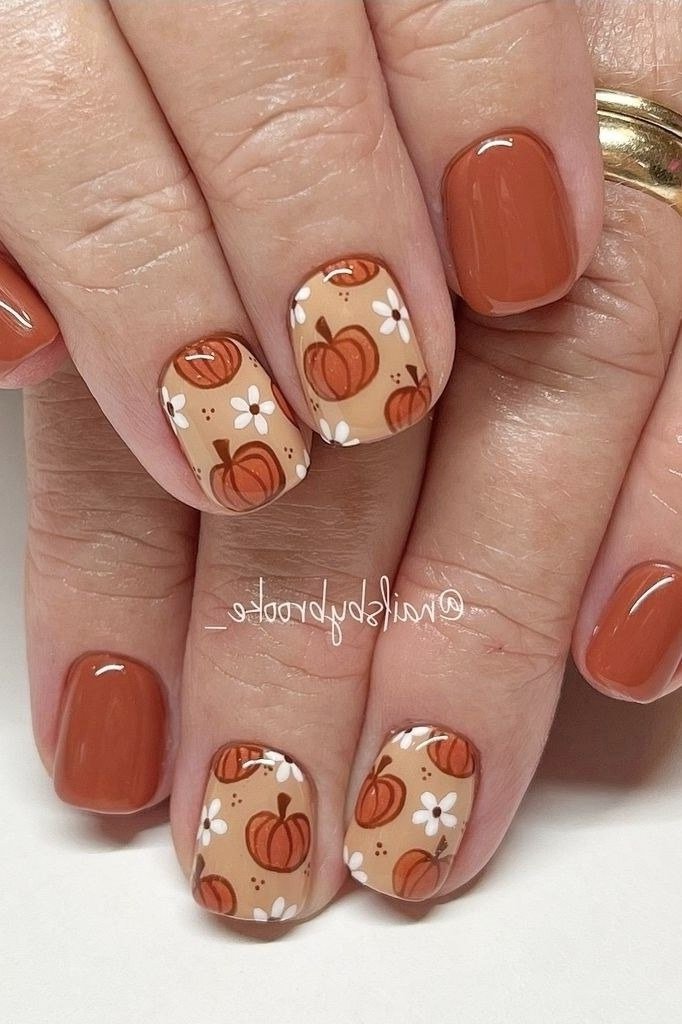 Warm orange short nails with pumpkin and fall floral nail art, glossy seasonal design.
