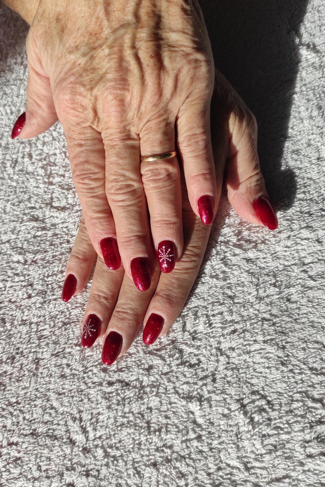 Red almond nails in sunlight for women over 60