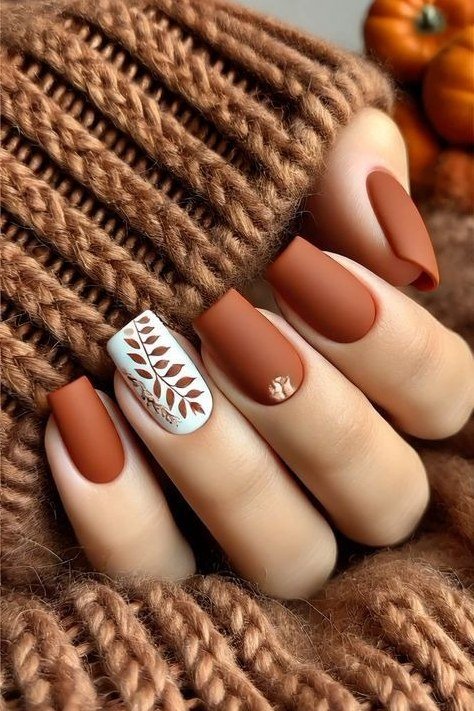 Rust nails with white leaf art on knit sweater, fall nail design for older women