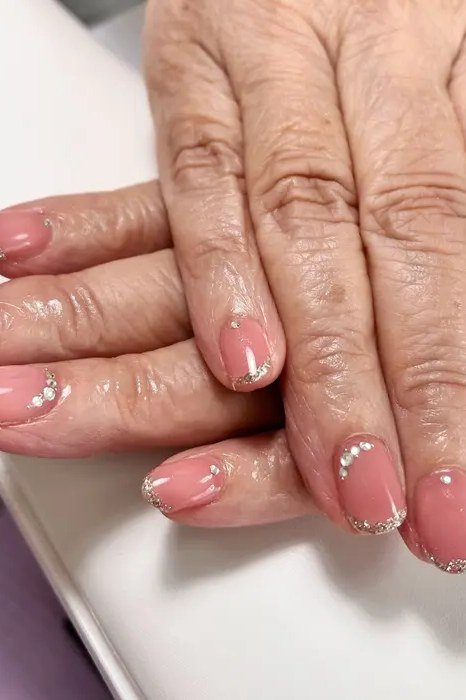 Coral pink nails with rhinestone dot accents