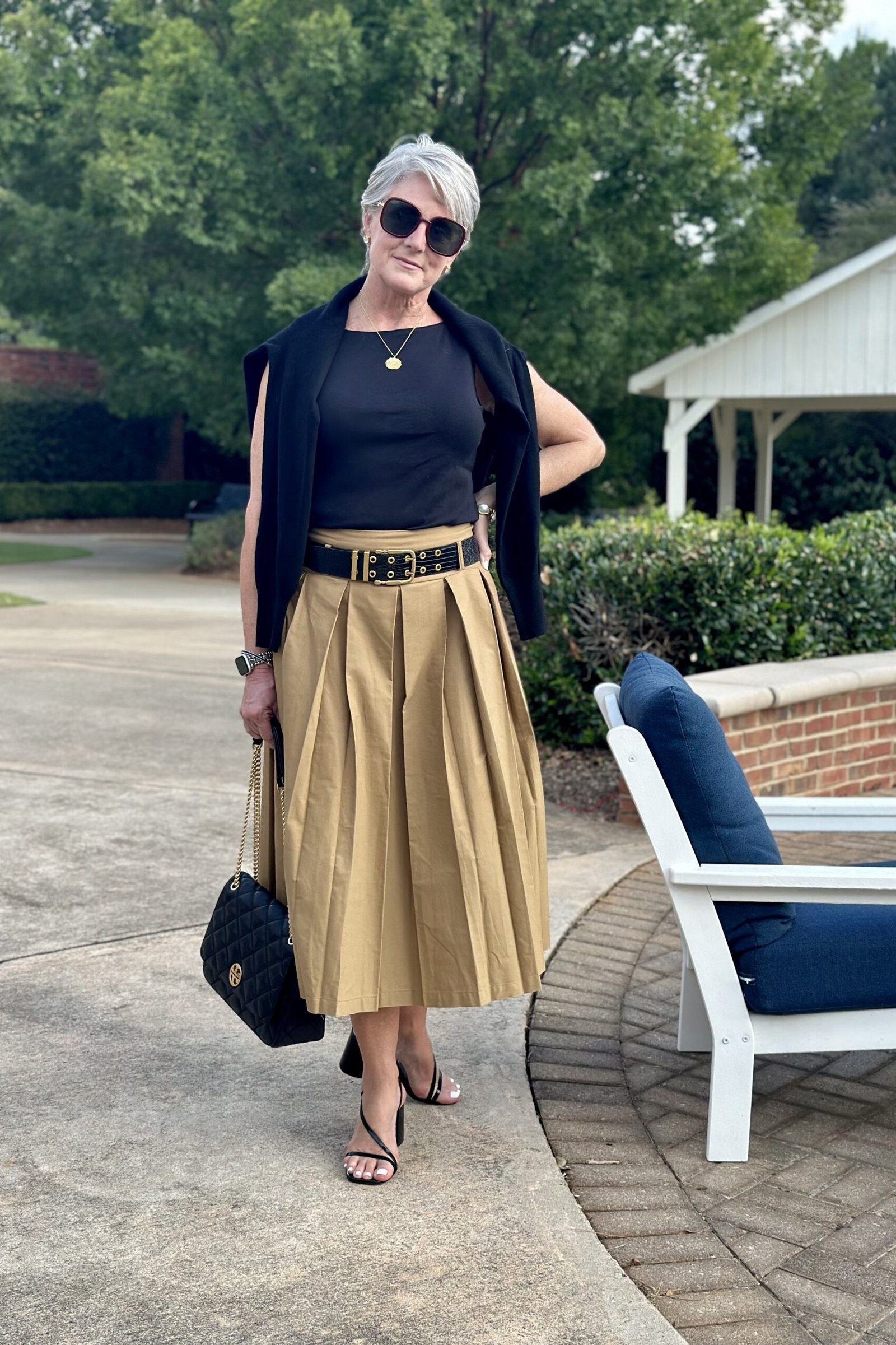 Black top with gold pleated midi skirt and shawl for women over 50, fall date night outfit