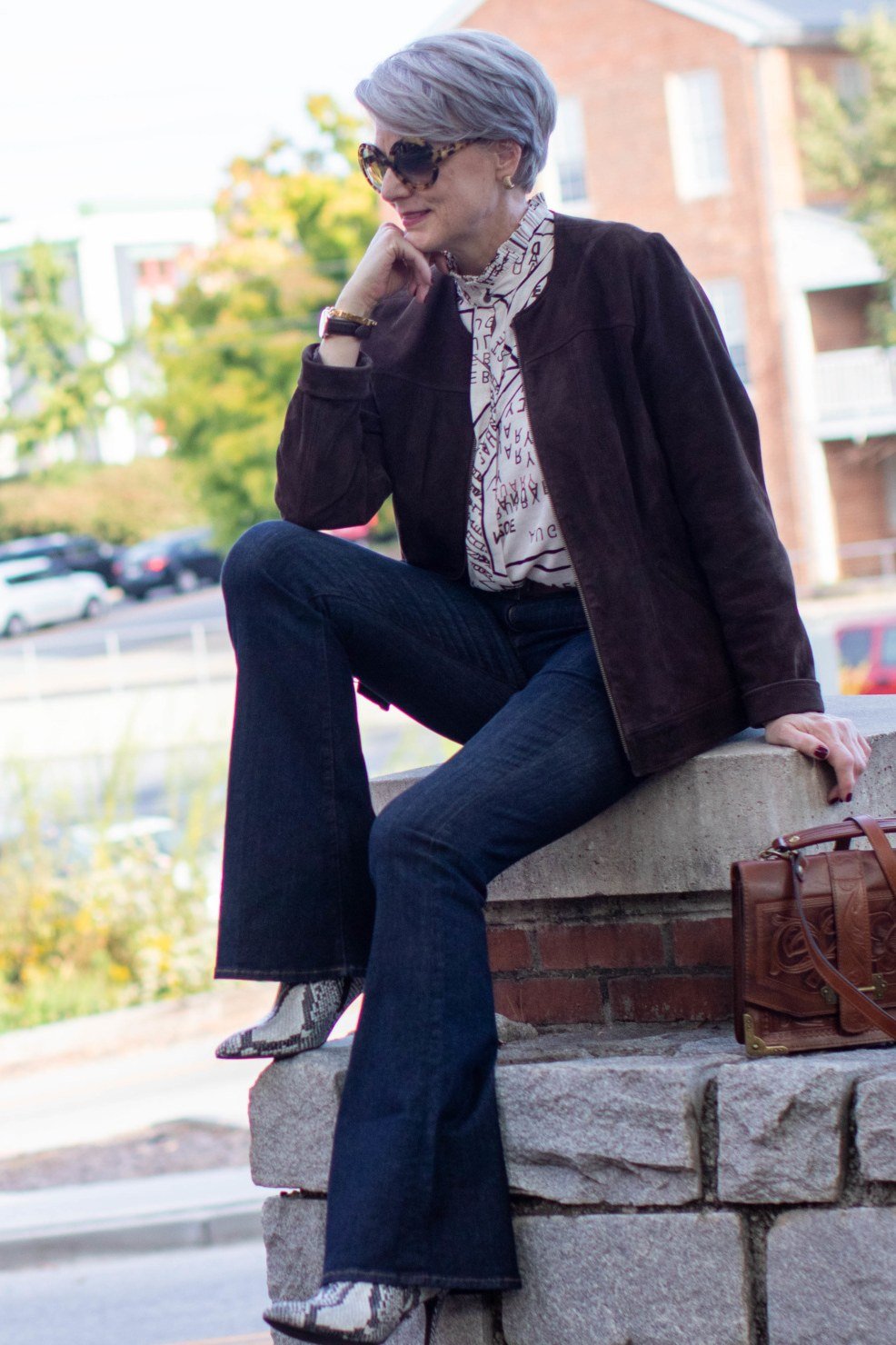 brown suede jacket, seated on a stone wall fall outfit for women over 60