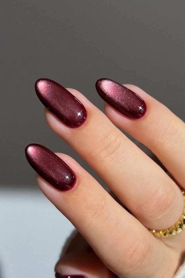 Shimmery burgundy almond with gold bracelet, burgundy fall nail idea for women over 60