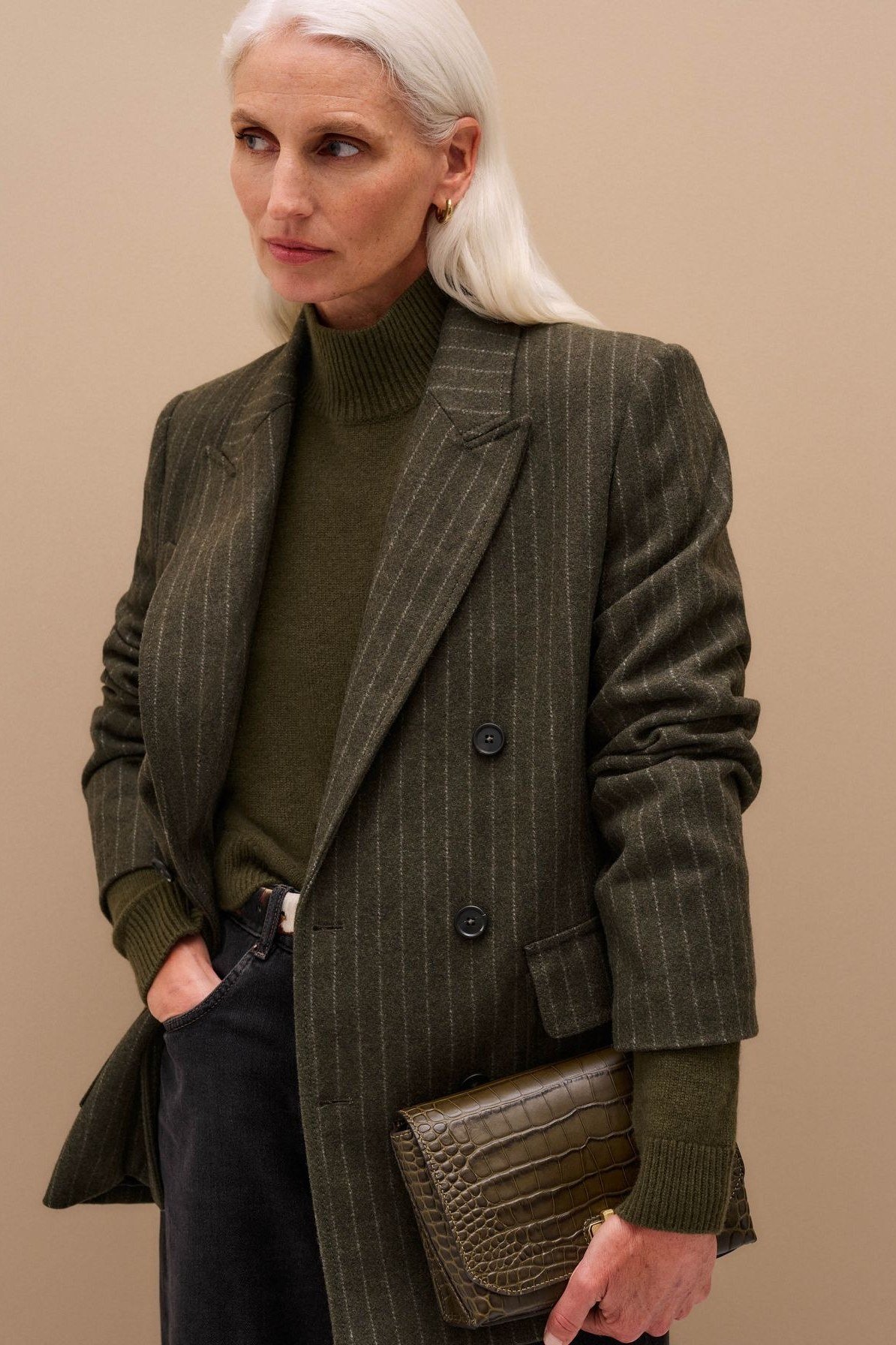 older woman in dark green pinstripe blazer with olive turtleneck