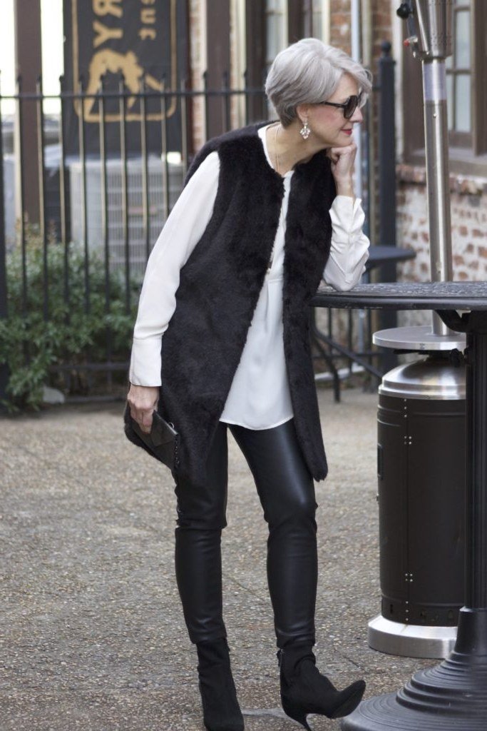 Gray-haired woman in black faux-fur vest over white top with black leather pants