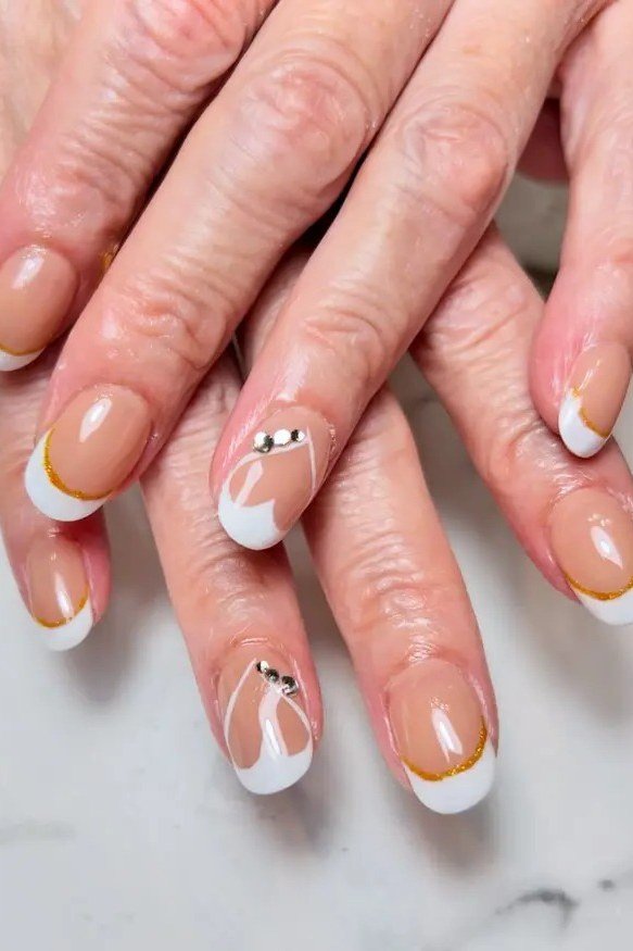 White and gold french with gem accents on mature hands