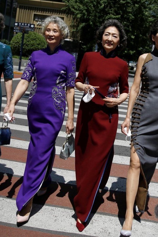 Four middle-aged women in long jewel-toned dresses crossing a city street - summer dress for women over 50