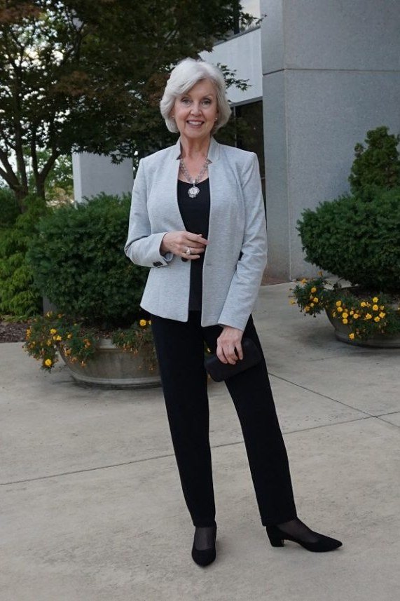 Light blue blazer black top black trousers, silver-haired woman outdoors - business casual work outfit for women over 50