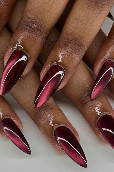 Cat-eye burgundy stiletto, deep skin tone, burgundy fall nail idea for women over 60
