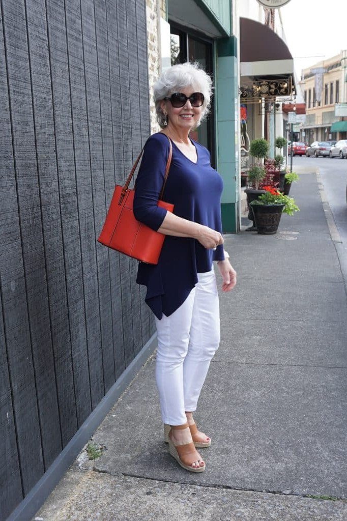 Woman over 50 wearing royal blue top with white jeans and red tote, everyday casual outfit idea