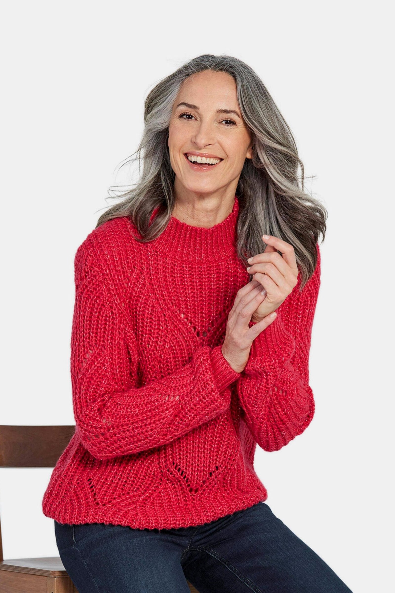 Scarlet cable-knit crew sweater seated indoors, cozy sweater outfit idea for women over 70