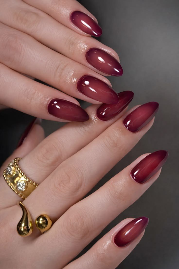 Solid burgundy almond nails with gold rings for women over 50