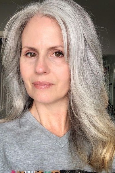 Long silver-gray layered hair with face framing for women over 50