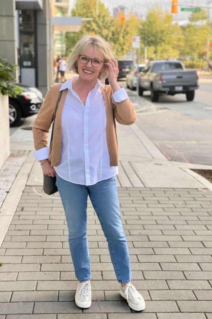 Woman over 60 wearing white shirt, tan jacket, light jeans, white sneakers