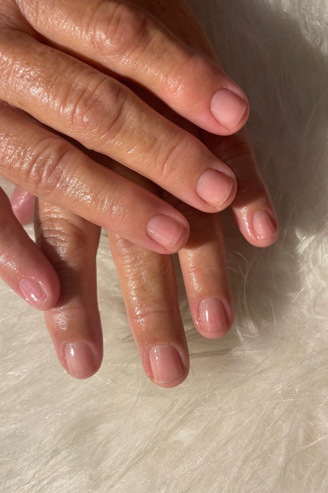 Sheer nude glossy nails on mature hands for women over 70