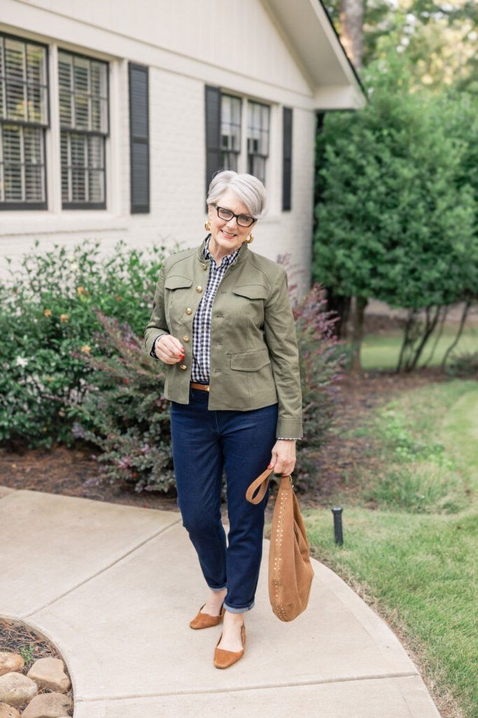 olive utility jacket gingham shirt dark jeans tan sling bag women over 50