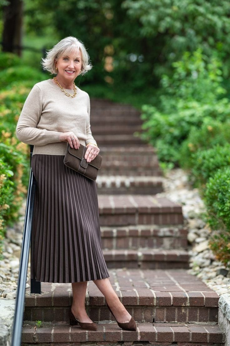 Cream sweater with brown pleated midi skirt on garden steps, woman over 50