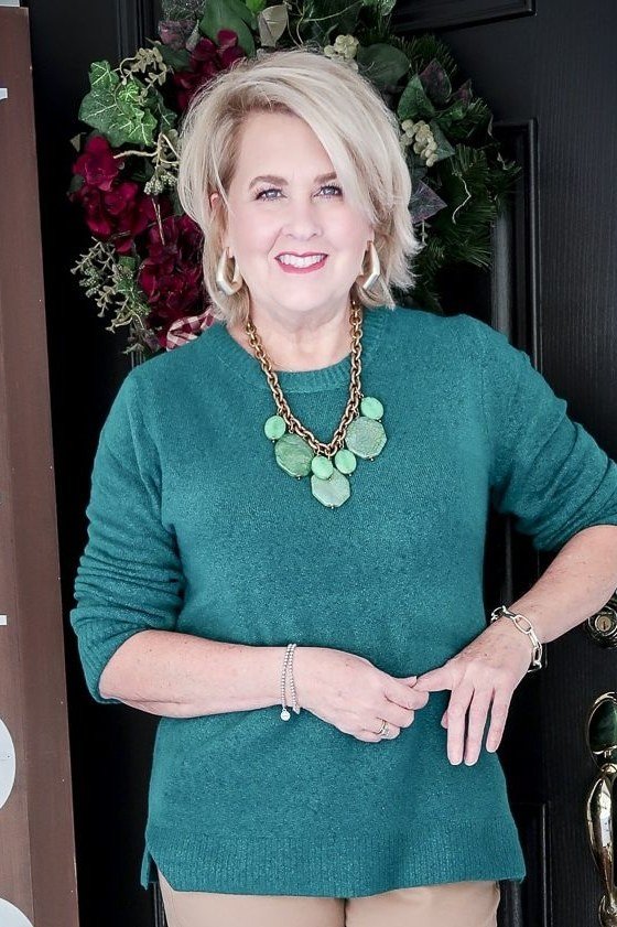 Teal knit sweater with statement green necklace on porch