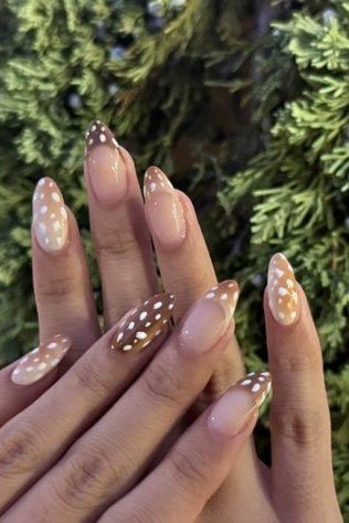 Pink almond nails with white spotted tips and greenery background fall nails