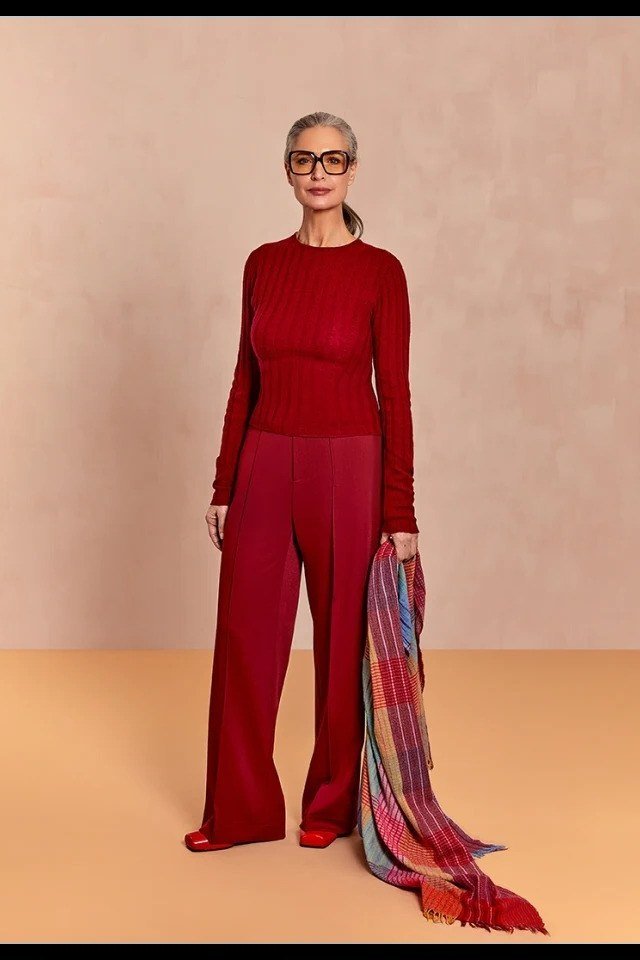 Older woman wearing a red turtleneck with red wide-leg trousers and a colorful scarf