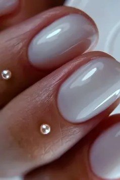 Milky white nails with tiny gem accents at the cuticle
