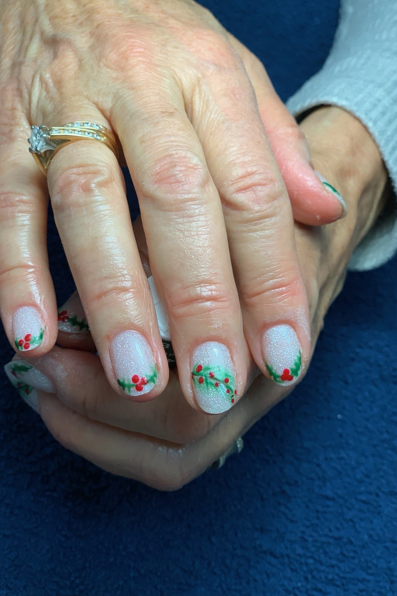Elderly hands, white nails with holly berry art - classy Christmas nail idea for women over 70