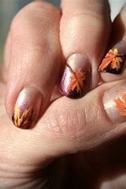 Short nails with colorful autumn leaf art on a dark moody background, glossy fall design.