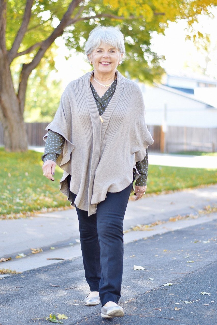 Cream knit poncho with dark trousers and white sneakers