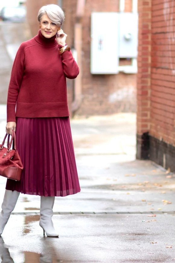 Stylish winter outfit for women over 60: red turtleneck with red pleated midi skirt and gray tights