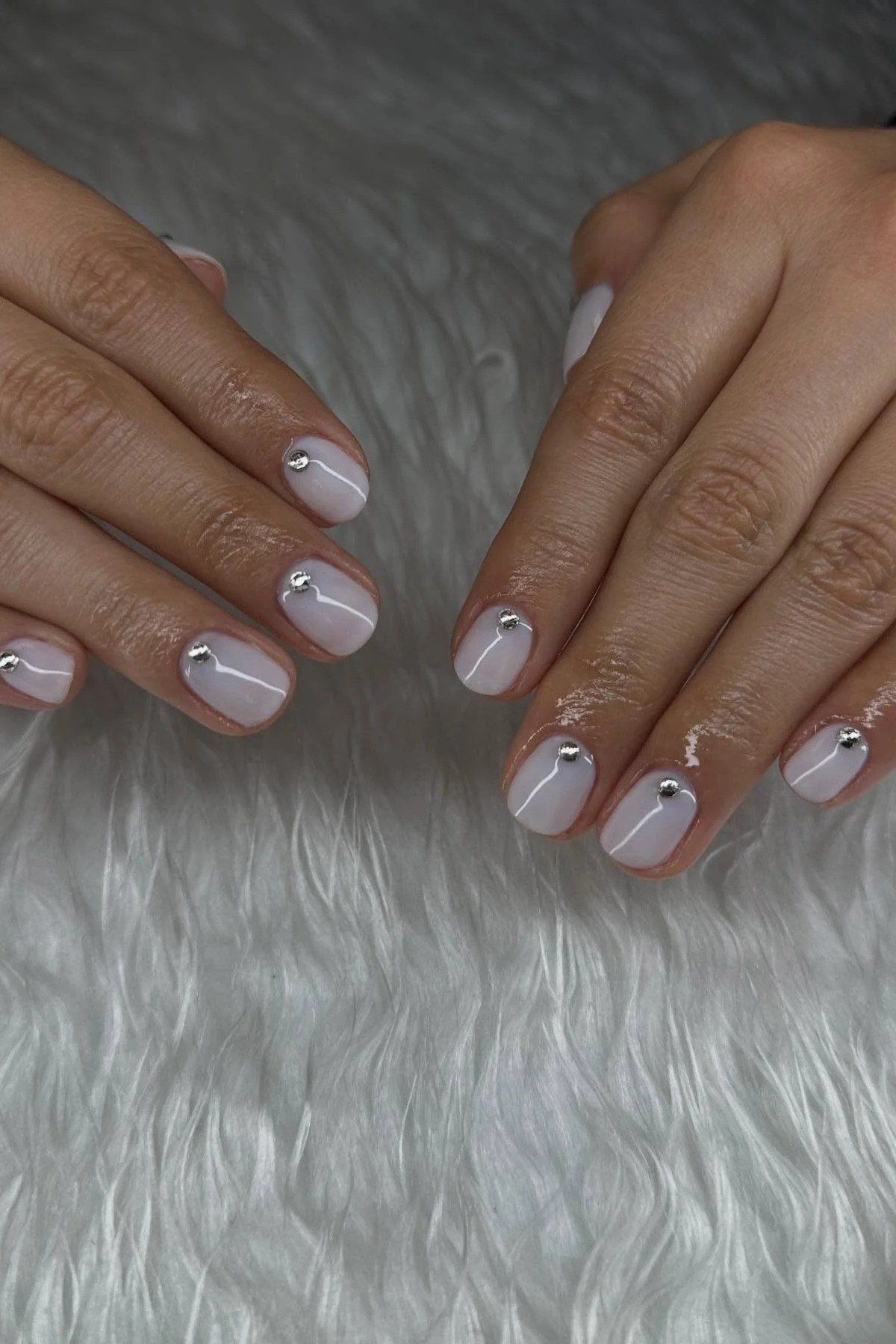 Milky white nails with tiny black dot accents on white fur