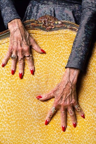 vibrant red nails on warm yellow fabric for older women