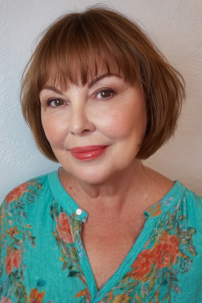 Auburn french bob with feathered bangs and turquoise floral top