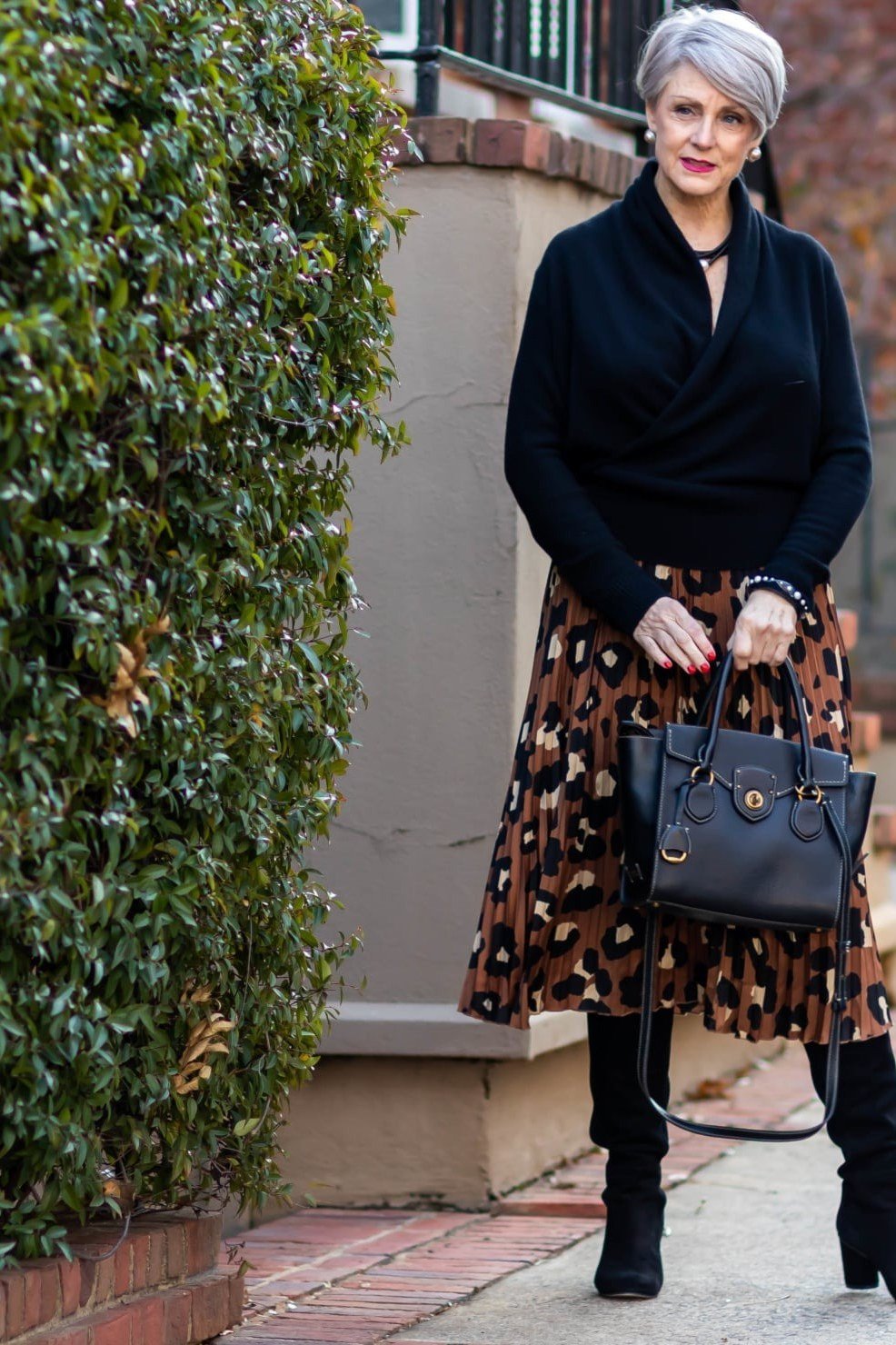 older woman in black wrap top with leopard midi skirt and black ankle boots