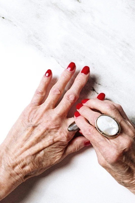 red nails with a bold ring on marble for older women