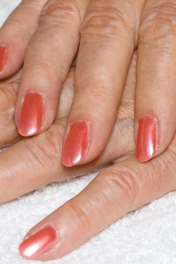 Warm coral nail polish on mature hands