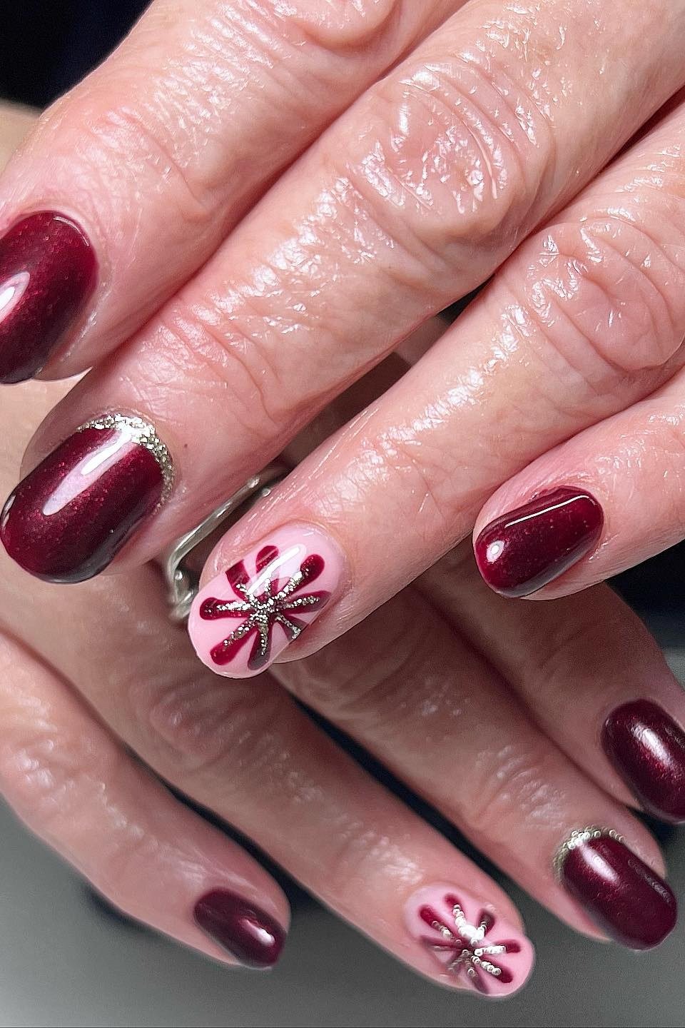 Burgundy with pink snowflake accent nail, mature hands - Christmas nail design for older women