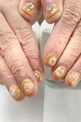 Nail art design for women over 60: gold foil nail art on older hands