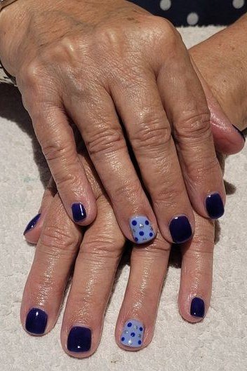 Navy nails with light blue polka dots on older woman's hands