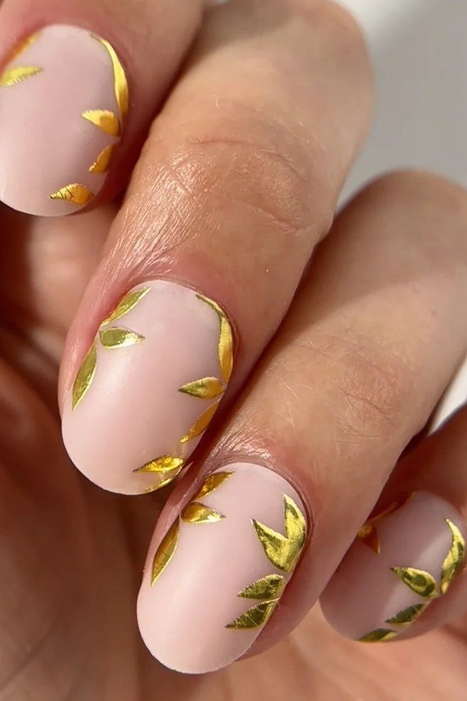 nude pink almond nails with gold leaf accents